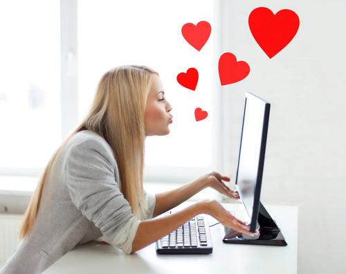 A blonde woman blowing kisses at a computer screen